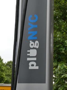 Electric car charger with logo plug NYC; the “u” in plug is the shape of an electrical plug.