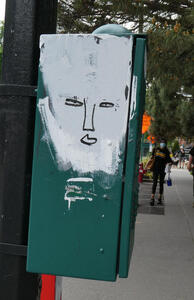 Utility box with a smear of white paint; a face is drawn in marker in the white paint.