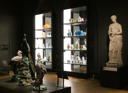 Display case with glassware; statue of woman at right
