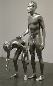 Stainless steel scullpture of two men, one bent over, the other with hand on the first man’s back