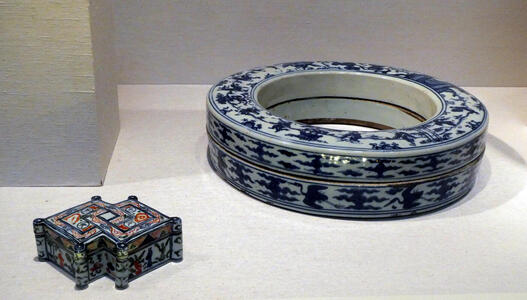 At left, box shaped like two interlocking diamonds; at right, a ring-shaped porcelain box with bue painting