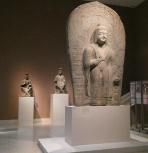 Foreground: large standing Buddha. Background: two seated royals (all stone sculptures)