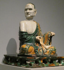 Porcelain seated Buddhist with grim visage