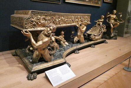 Large harpsichord supported by gold scultpures of people.