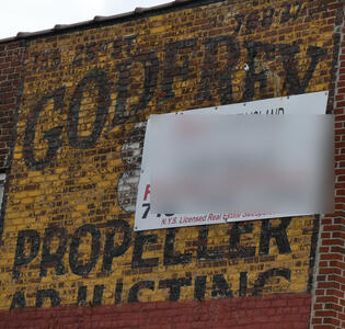 Faded sign on brick wall: Godfrey Propeller Adjusting