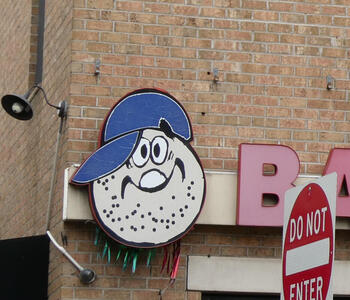 Cartoon poppy seed bagel wearing a blue baseball cap