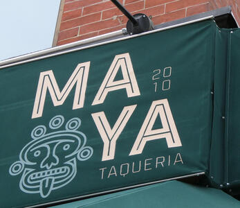 Sign for MAYA Taqueria, with mayan mask at left