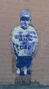 Wall painting of boy in T-shirt with text “Don’t Deport My Dad”