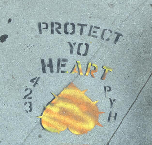 Stenciled PROTECT YO HEART, with ART in gold color, and an  upside down gold colored heart beneath the words