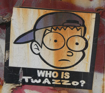 head of cartoon boy with wide eyes and blue baseball cap worn backwards. Text: WHO IS TWAZZO?