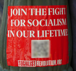 Red sticker with white text: JOIN THE FIGHT FOR SOCIALIS IN OUR LIFETIME SOCAILISTREVOLUTION.ORG