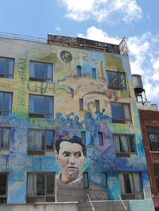 Multi-story building painted with face of latino-looking man at bottom
