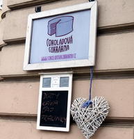 Sign for Čokoládová Cukrárna, with heart made out of twine hanging from sign.