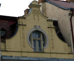 Topof building with round window and woman's face in reliefwork above window
