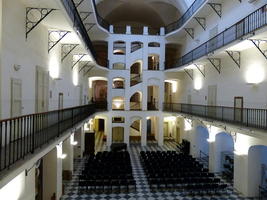 Main stage of museum with rows of chairs and wooden artistic scaffolding around stairway