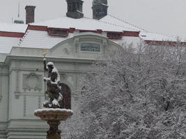 Snow-covered statue of Neptune, with tree limbs at right