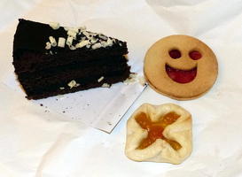 Chocolate cake, smiley face cookie, and square cookie with filled “X”.