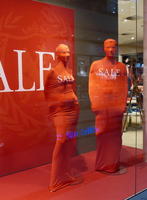 Department store mannequins entirely enclosed in red cloth, labeled “Sale”