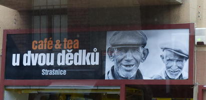 Two smiling old men on sign “Café & tea u dvou dědků” (Coffee and tea Chez Two Old Guys)