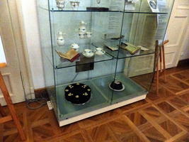 Display case with chocolate cakes on bottom shelf, tea service on middle shelf