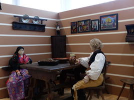 Man and woman mannequin seated at country house table; dressed in traditional Czech dress