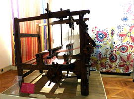 Loom in foreground, cloth hanging on wall in background