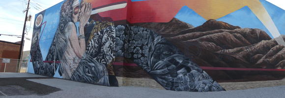 Wall mural showing woman kissing man; fades into a landscape