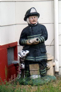 Small traditional statue of a firefighter holding a hose.