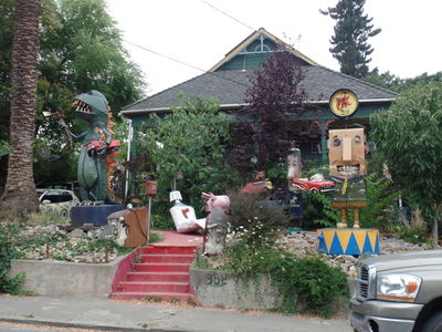 Artists' house with dinosaur, used car salesman, toothpaste tube, and several other sculptures.