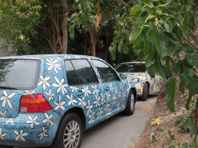 Artists' cars; one is blue with white flowers; other is yellow with blue geometric designs.