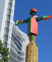 Column with “wooden toy soldier”-type figure on top. San Jose City Hall in background.