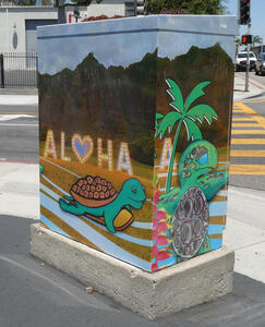 Utility box with turtle and palm tree, with word ALOHA in background