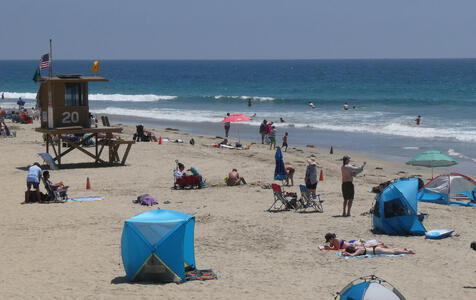 Tents and peope on beach; lifeguard station at background left