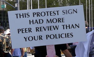 This protest sign had more peer review than your policies.