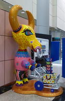 Brightly painted statue of a bull with a shopping cart