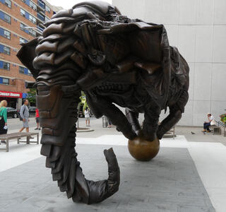 Bronze sculpture of elephant balancing on a ball. It looks as if it were made of leather couch material