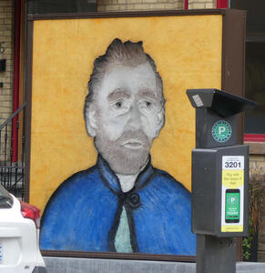 Large wall painting of a man with a beard, looking somewhat like Vincent Van Gogh.