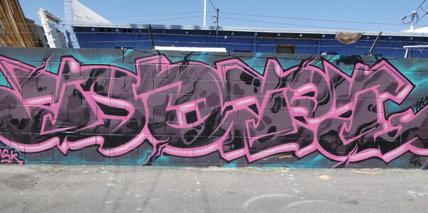 Large graffiti signature in dark gray with pink outline.