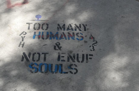 Stenciled on sidewalk: Too Many Humans & Not Enuf Souls