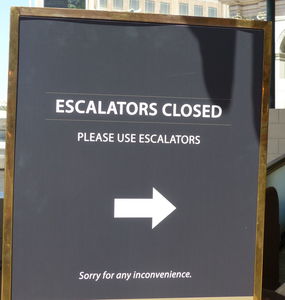 Sign: “Escalators Closed. Please use esclators” with arrow under the text.