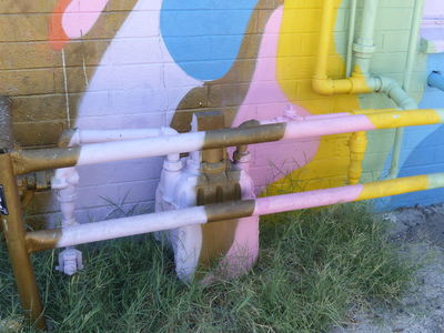painted gas pipes and meters at base of wall art