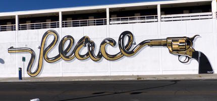 Wall painting of gun whose barrel is twisted into the word “peace.”