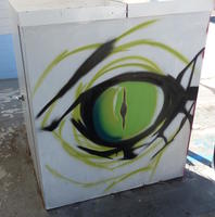 Green eye with vertical slit; painted on a utility box