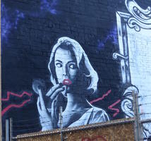 Wall art: woman applying lipstick while looking furtively to side.