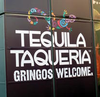 Sign for Tequila Taqueria with curved font and a multicoloured lizard