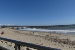 View across beach to wooden pier in distance, extending out over the ocean