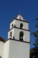 White adobe bell tower with brown and white dome top
