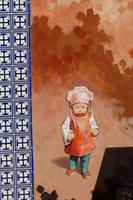 Closeup of mural showing child in green pants and orange shirt, with white chef-style hat