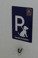 Large capital P  as in Parking signs, attached to dog on leash. Text: “dog parking place”