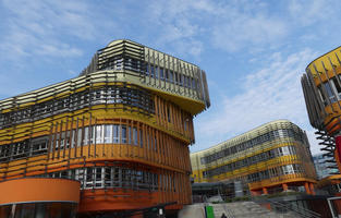Long view showing curved exterior of yellow to orange building